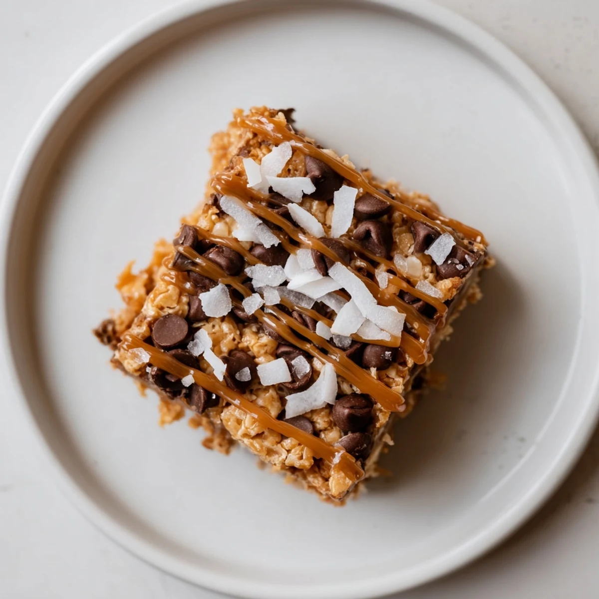 A close-up of a tray of delicious 7-Layer Magic Bars topped with a flowing caramel drizzle.