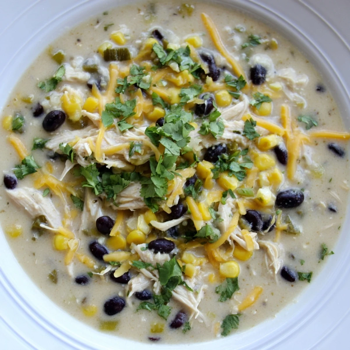 A close-up view of flavorful Chicken Poblano Soup, with visible black beans and golden corn kernels.