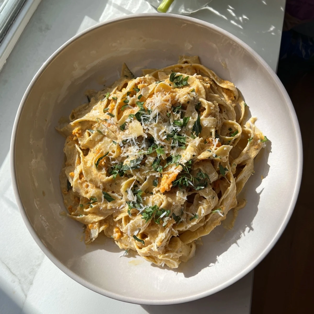 Healthy Creamy Pumpkin Sage Holiday Pasta, a warm bowl with Parmesan and fresh sage garnish.