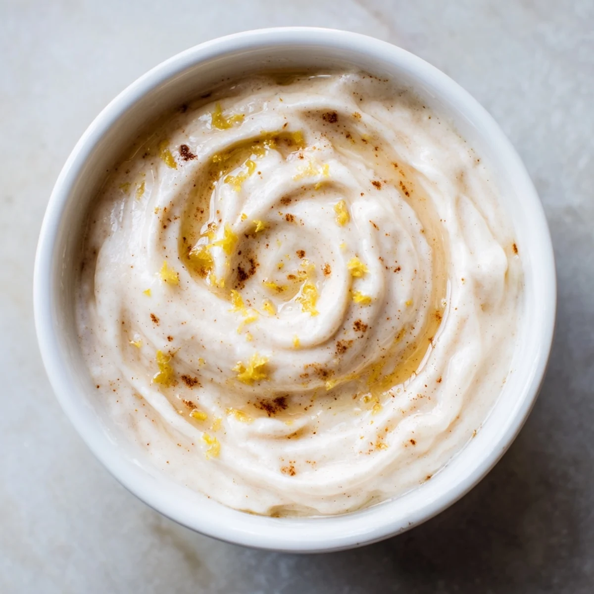 Creamy Greek Yogurt Fruit Dip, speckled with lemon zest, ready to be scooped with fresh strawberries.