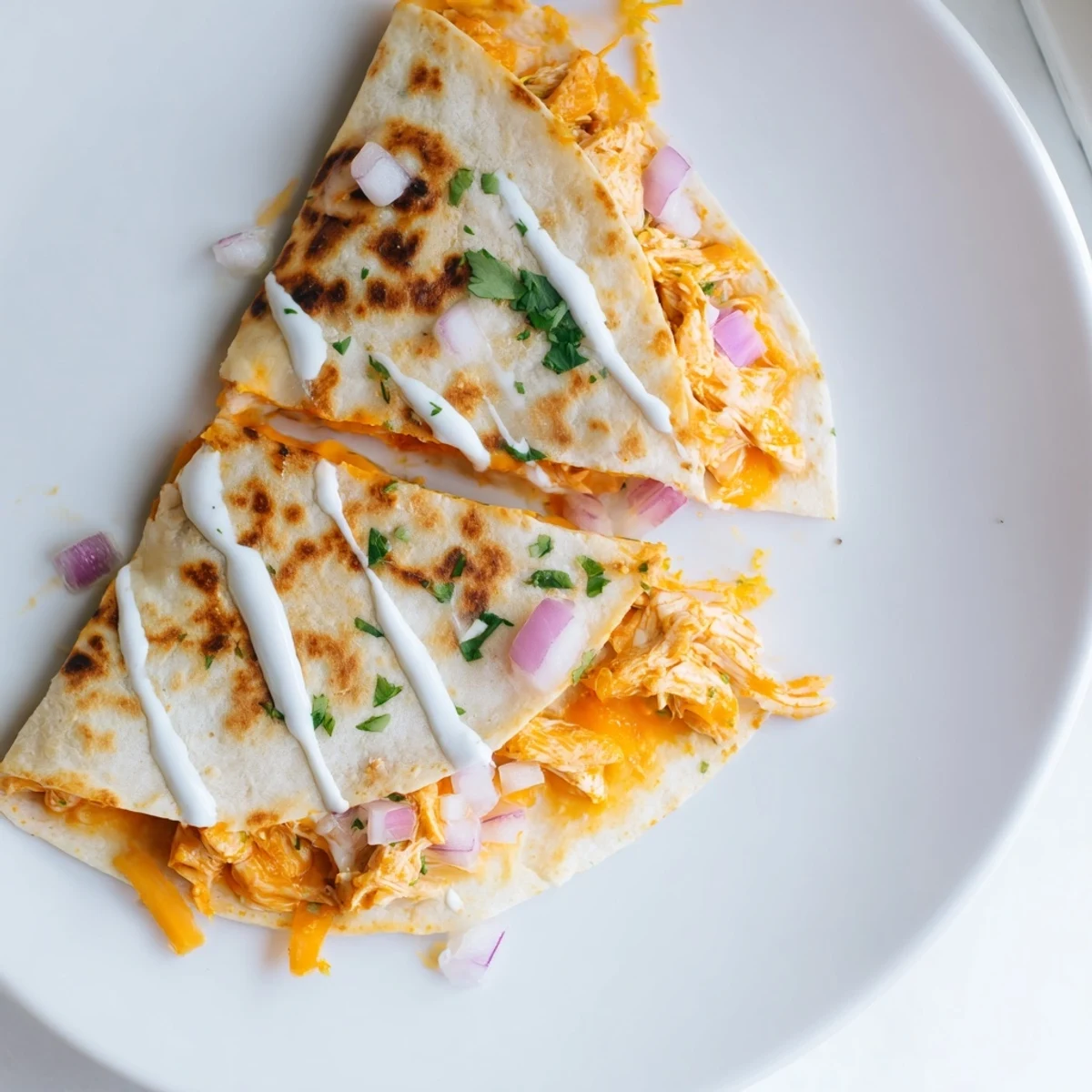 A close-up of a sizzling Buffalo chicken quesadilla, brimming with melted cheese and chicken filling.