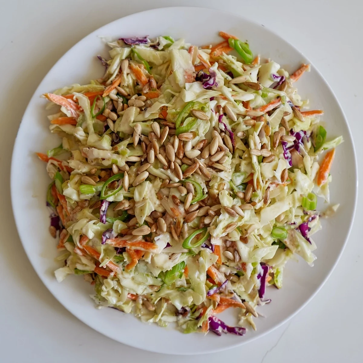 Close-up shot shows a bowl of homemade crunchy coleslaw salad beautifully topped with sunflower seeds.