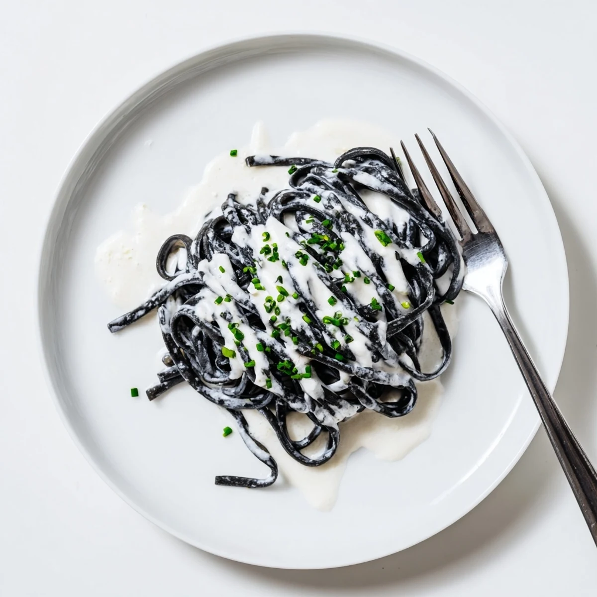 Creamy sauce clings to al dente Squid Ink Pasta, topped with chives and lemon wedges for a dramatic main dish.