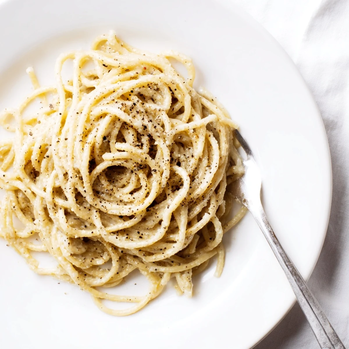 Spaghetti Cacio e Pepe served hot, topped with extra cheese and a crack of black pepper.  