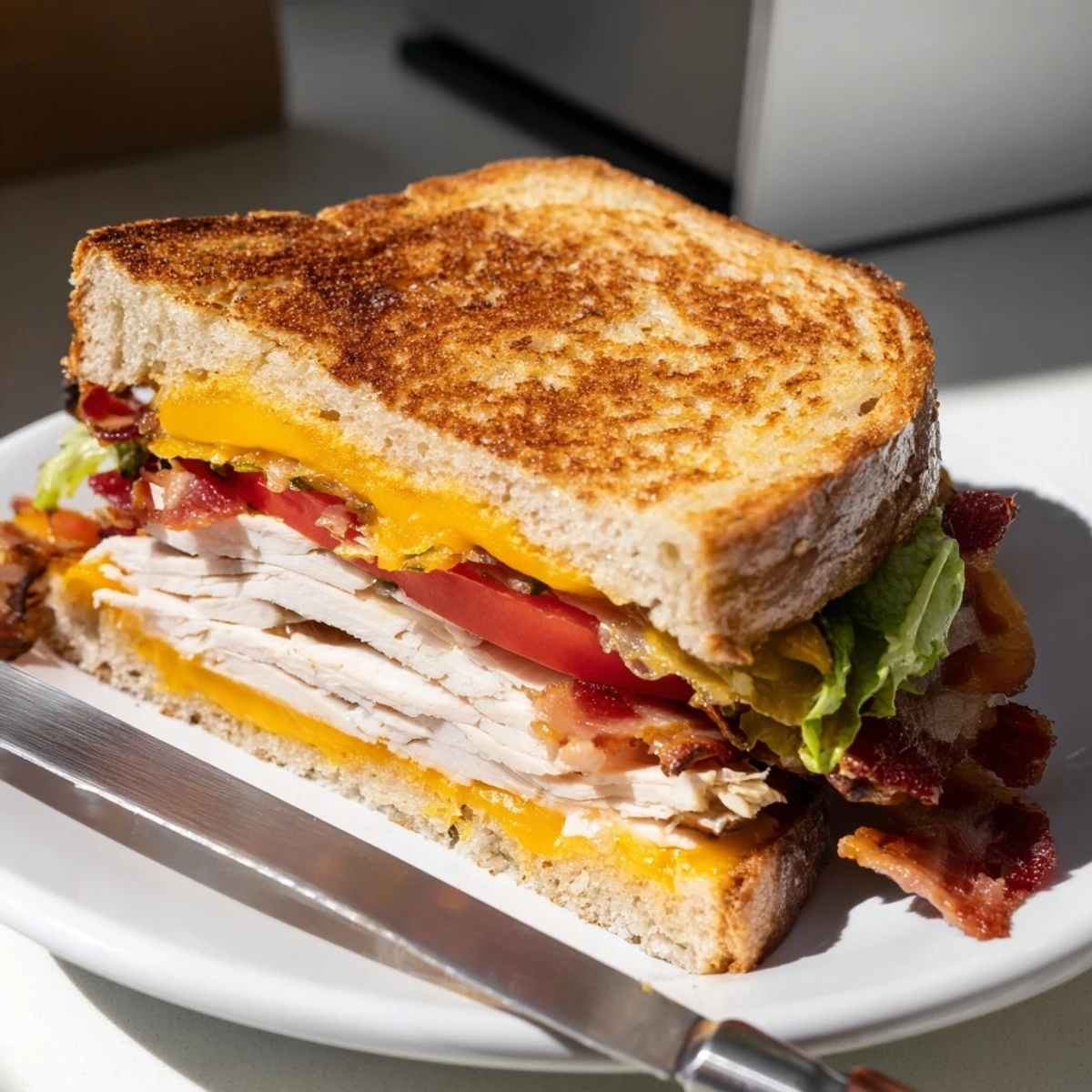 Golden sourdough slices encase melted cheddar, roasted turkey, crispy bacon, fresh lettuce, and juicy tomato in this Turkey Club Grilled Cheese.