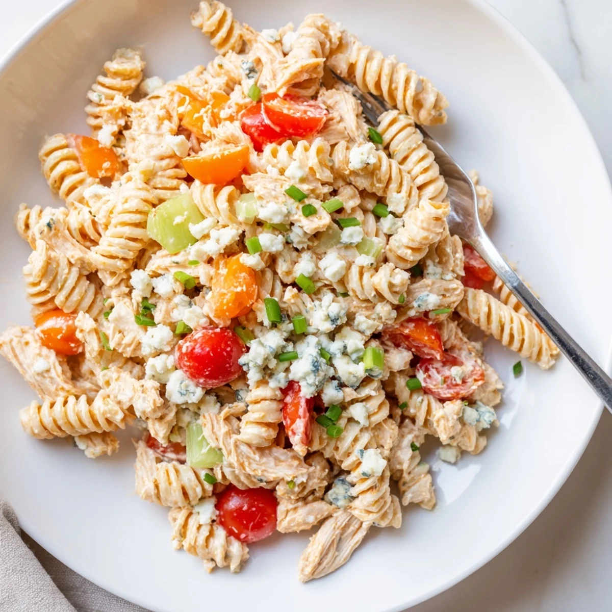 Creamy Buffalo Chicken Pasta Salad with celery, bell peppers, and ranch dressing in a chilled bowl for potlucks.