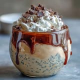 Creamy vanilla bean frappuccino overnight oats layered in a jar with whipped cream and chocolate shavings for a dreamy breakfast or dessert.