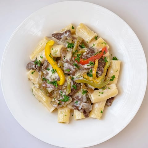 A steaming bowl of Philly Cheese Steak Pasta, with melted cheese and tender beef visible.