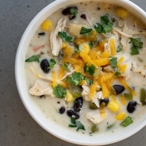 Steaming bowl of creamy Chicken Poblano Soup, garnished with cilantro, ready for a comforting meal.