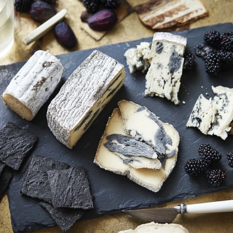 Elegant monochrome gray stone cheese board featuring ash-rinded cheeses, perfect for entertaining.