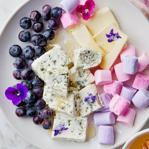 A Lavender Haze Dreamscape cheese board, perfect for gatherings, with creamy cheeses and pastel fruits.