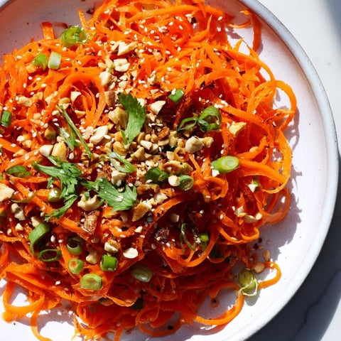 Vibrant, shredded Spicy Carrot Salad in a bowl, showcasing the bright orange carrots and fresh herbs.