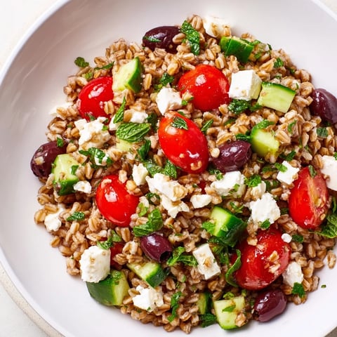 Farro Salad Mediterranean bowl with nutty grains, juicy tomatoes, crisp cucumbers, briny Kalamata olives, and creamy feta in zesty lemon-oregano dressing.