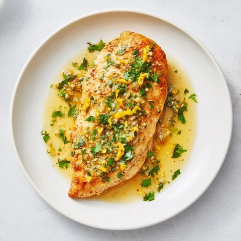 Golden pan-seared Lemon Pepper Chicken breasts glistening with a buttery lemon sauce and fresh parsley garnish.