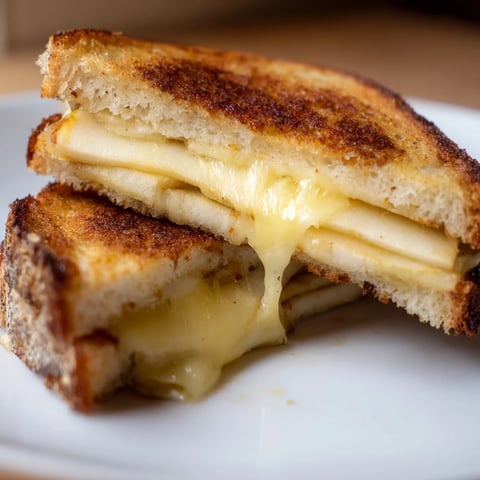 Golden-brown sourdough sandwiches with melted smoked Gouda and crisp apple slices, served warm on a rustic plate.  