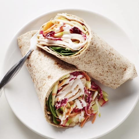 Freshly assembled cranberry apple slaw turkey wraps, showcasing layers of texture and flavor, perfect for a picnic.