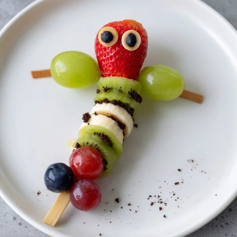 Sweet, assembled Caterpillar Fruit Skewer Track: fresh fruit arranged as friendly caterpillar snacks on a winding path.