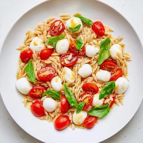 Tossed Caprese Orzo Salad featuring vibrant cherry tomatoes and mozzarella, drizzled in balsamic.