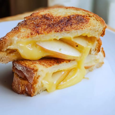 A close-up of a buttery grilled cheese sandwich with gooey smoked Gouda and tart apple, ready for lunch.  