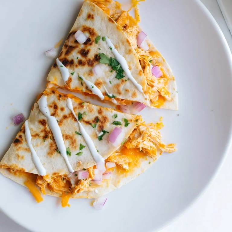 A close-up of a sizzling Buffalo chicken quesadilla, brimming with melted cheese and chicken filling.