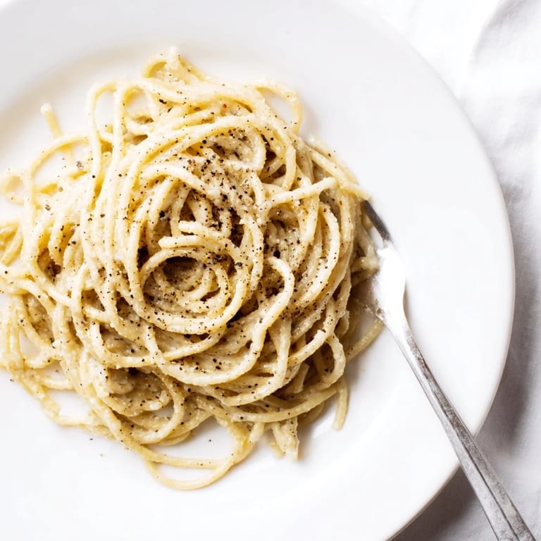 Spaghetti Cacio e Pepe served hot, topped with extra cheese and a crack of black pepper.  