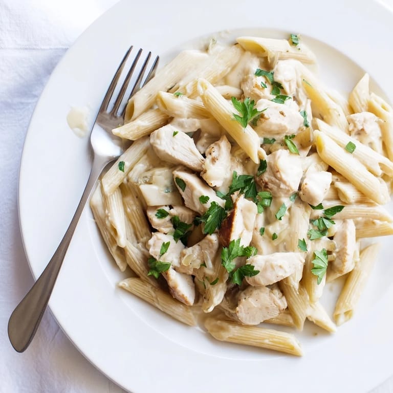 Roasted Garlic Chicken Penne features tender penne, juicy chicken, and silky garlic cream sauce garnished with fresh parsley and parmesan.