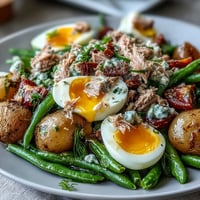 A vibrant Spring Niçoise Salad with tender tuna, crisp green beans, and soft-boiled eggs, drizzled with zesty Dijon vinaigrette.